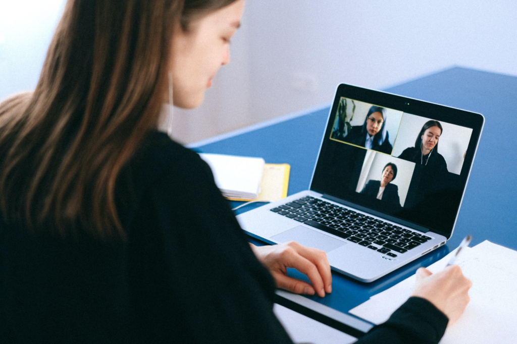 A person communicates with others via video call on a laptop